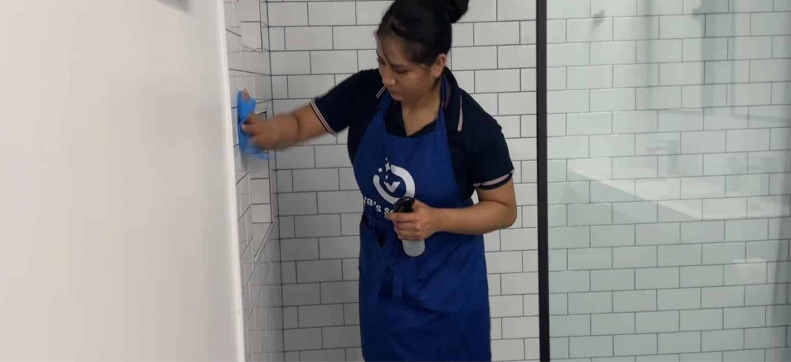 A Val’s Services technician carefully cleaning a tiled shower
